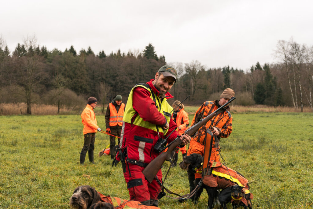 Hundeführer lädt sein Gewehr, die Hunde sind noch an der Leine, die Drückjagd beginnt gleich